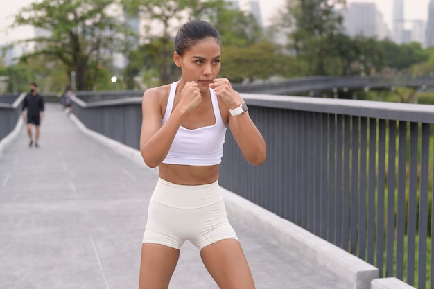 Una giovane donna fitness nella boxe di abbigliamento sportivo nel parco cittadino Salute e stili di vita