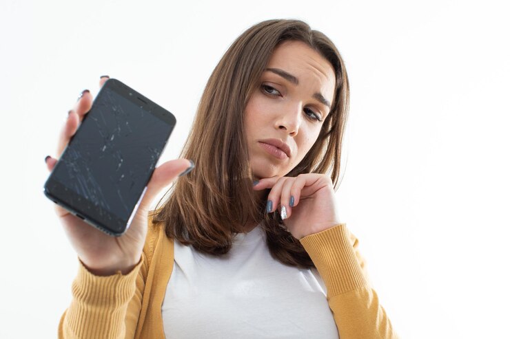 Una giovane donna fracassato il suo telefono La bruna tiene il telefono nelle sue mani su uno sfondo bianco isolato Servizio di riparazione di apparecchiature elettriche