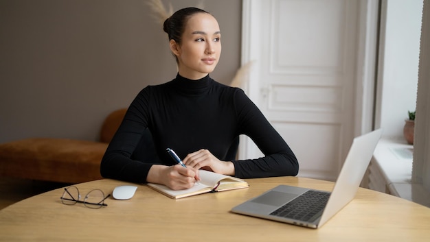 Una giovane donna freelance che chatta online scrive un messaggio utilizza un laptop in un posto di lavoro in ufficio