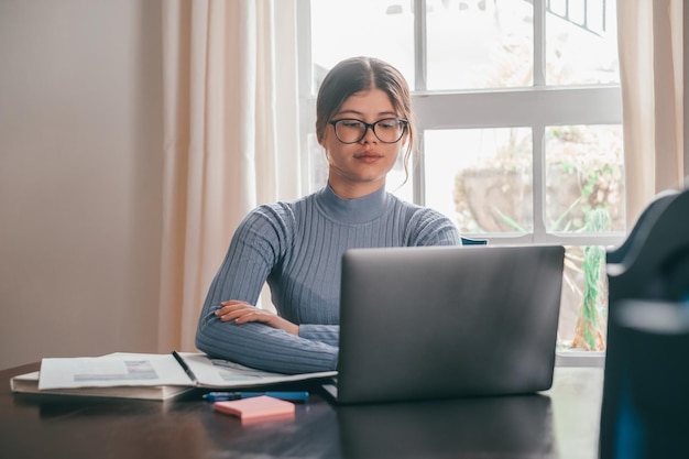 Una giovane donna graziosa che studia e fa i compiti a casa sul tavolo Adolescente femmina che utilizza laptop o computer che naviga in rete al coperto