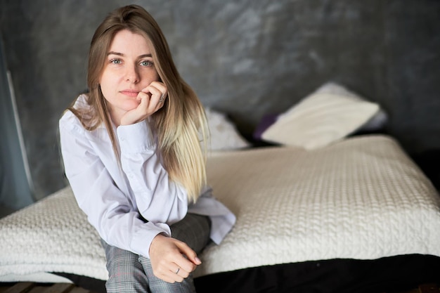 Una giovane donna guarda attentamente nella telecamera sullo sfondo del letto Concetto di violenza domestica