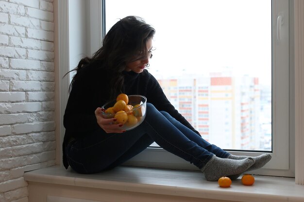 Una giovane donna guarda fuori dalla finestra di un nuovo appartamento