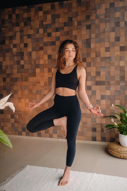 Una giovane donna in abiti neri sta facendo yoga in una moderna palestra. Il concetto di salute.