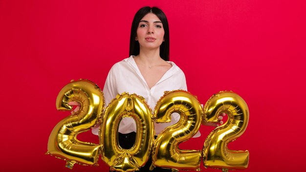 Una giovane donna in camicia bianca tiene in mano i numeri del prossimo capodanno 2022