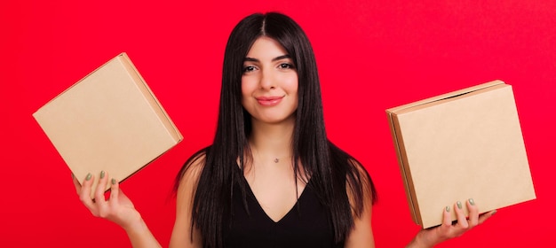 Una giovane donna in due confezioni regalo su sfondo rosso Foto panoramica