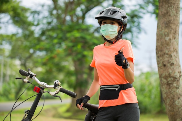 Una giovane donna in maschera medica va in bicicletta