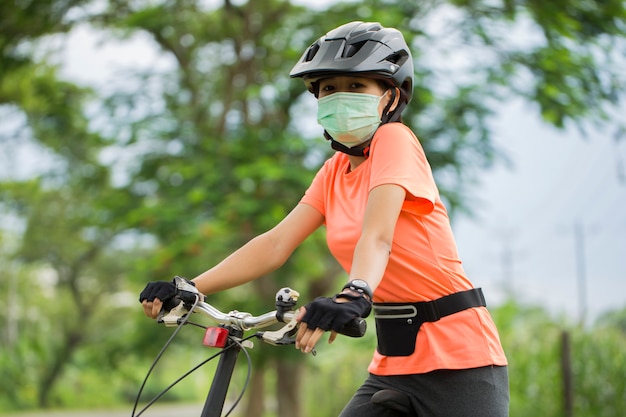Una giovane donna in maschera medica va in bicicletta