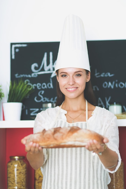 Una giovane donna in piedi nella sua cucina in possesso di pane Una giovane donna