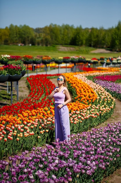 Una giovane donna in un abito rosa si trova in un campo fiorito di tulipani Primavera