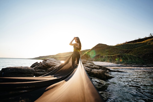 Una giovane donna in un vestito nero si trova nell'acqua in riva al mare Foto di alta qualità