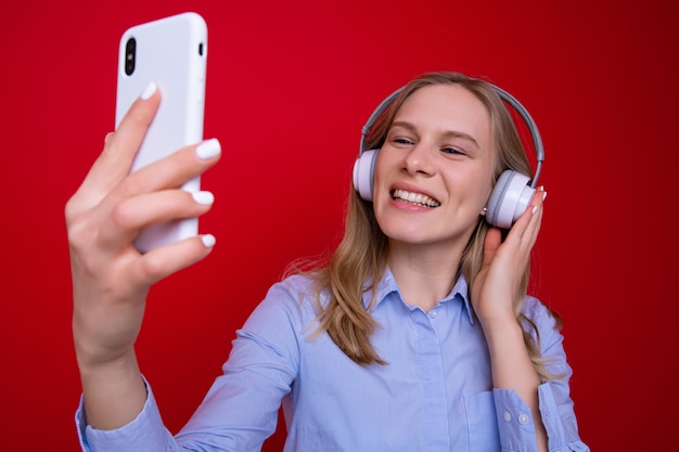 Una giovane donna in una camicia ascolta la musica dal suo telefono