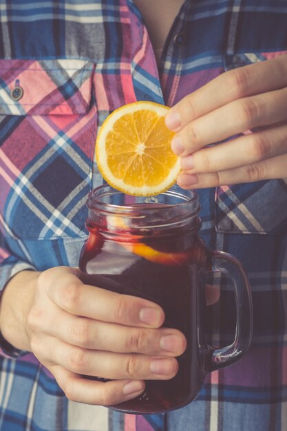 Una giovane donna in una camicia tiene tra le mani una tazza di vin brulè fatto in casa