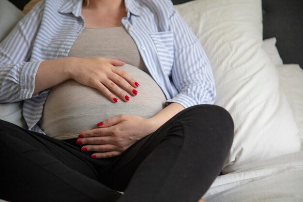 Una giovane donna incinta che riposa a casa seduta su un letto in attesa della madre