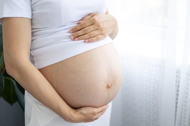 una giovane donna incinta sana in una fase avanzata si abbraccia lo stomaco con le mani una gravidanza sana