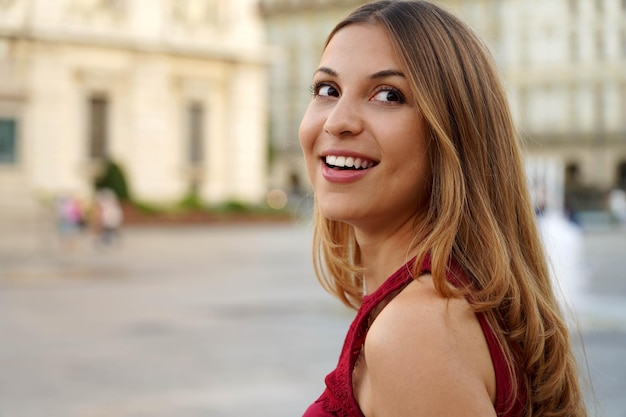 Una giovane donna intelligente e interessata gira la testa mentre cammina sullo sfondo urbano