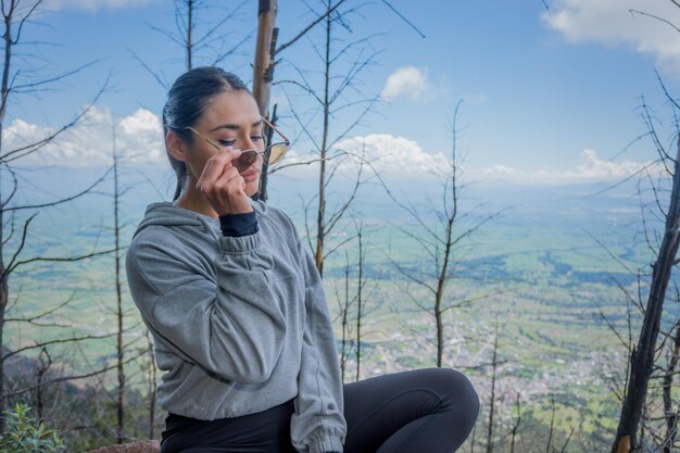 Una giovane donna ispanica seduta su una roccia e godersi la bellissima natura