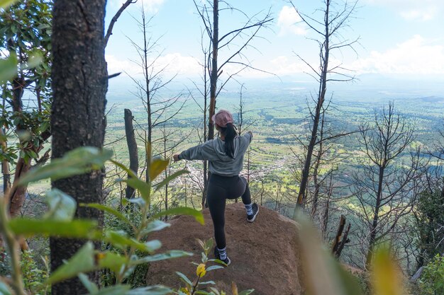 Una giovane donna ispanica seduta su una roccia e godersi la bellissima natura