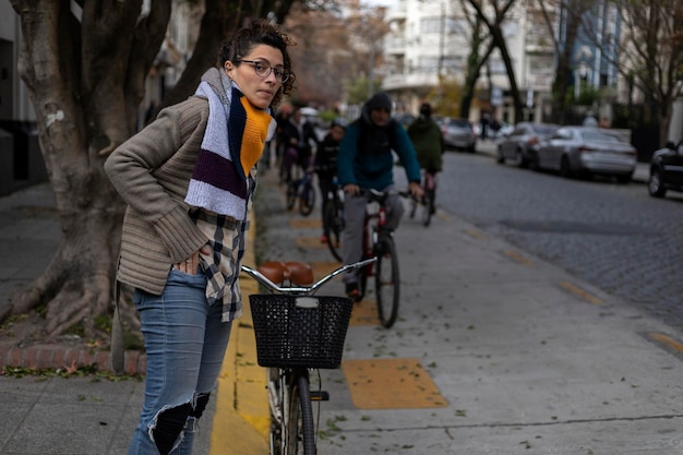 Una giovane donna latinoamericana attende sul lato della pista ciclabile mentre i ciclisti le passano accanto