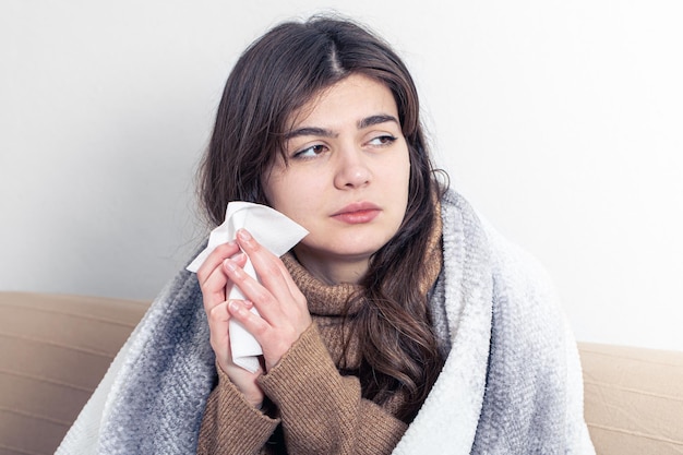 Una giovane donna malata a casa sul divano con il raffreddore