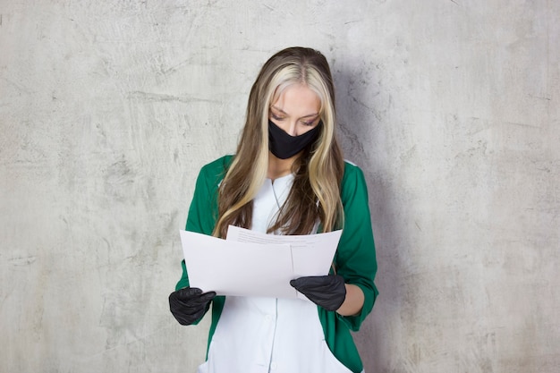 Una giovane donna medico in un camice medico e una maschera. un giovane specialista in guanti medicali