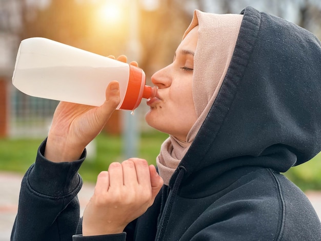 Una giovane donna musulmana beve acqua dopo il suo allenamento mattutino