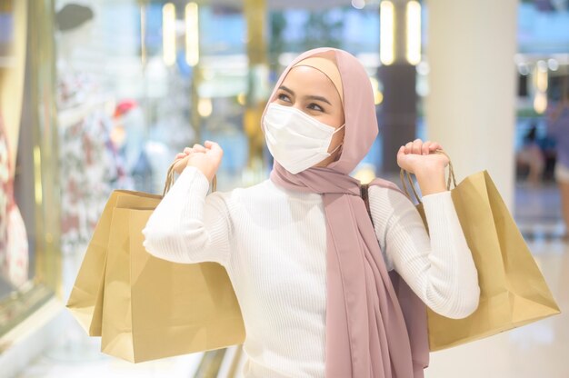 Una giovane donna musulmana che indossa una maschera protettiva nel centro commerciale