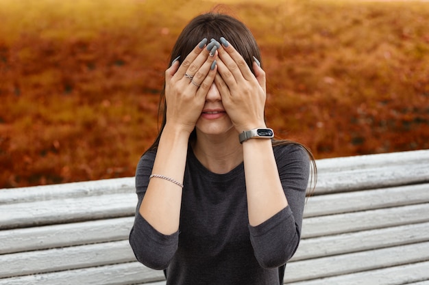 Una giovane donna nel parco si coprì il viso con le mani