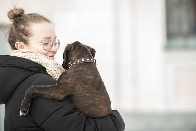 una giovane donna nella stagione fredda durante una passeggiata con in braccio un piccolo cucciolo