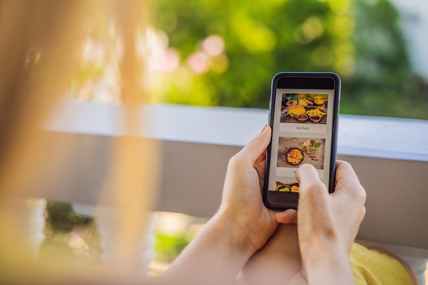 Una giovane donna ordina cibo per il pranzo online usando uno smartphone