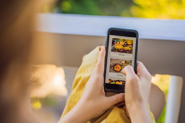 Una giovane donna ordina cibo per il pranzo online usando uno smartphone