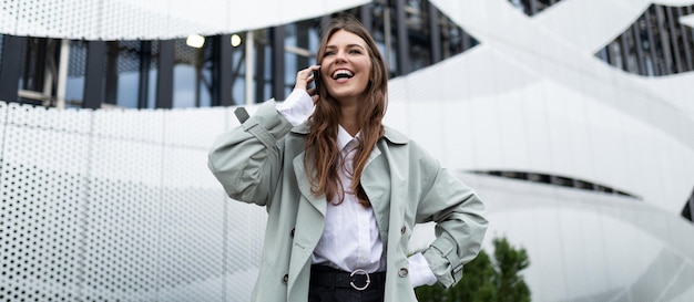 Una giovane donna parla su un telefono cellulare con un ampio sorriso sul viso sullo sfondo di un