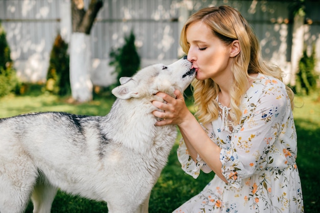 Una giovane donna romantica in posa con un cane sull'erba