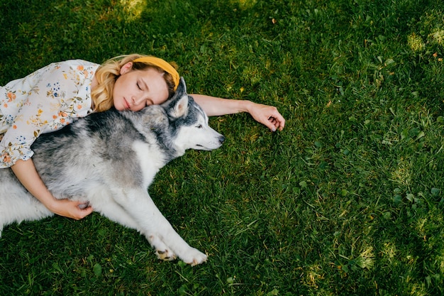 Una giovane donna romantica sdraiata con un cane sull'erba