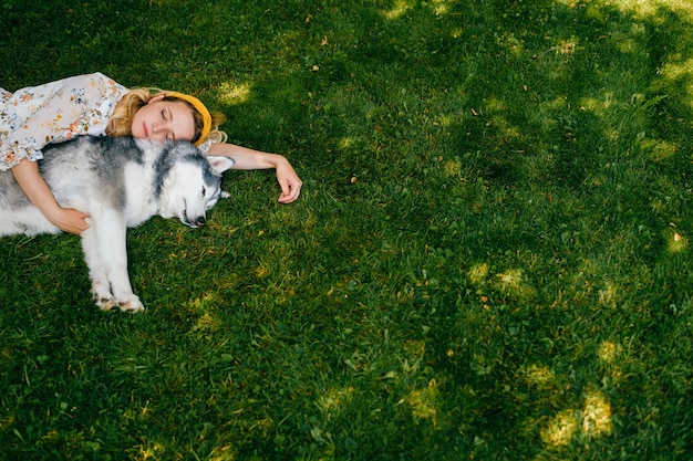 Una giovane donna romantica sdraiata con un cane sull'erba