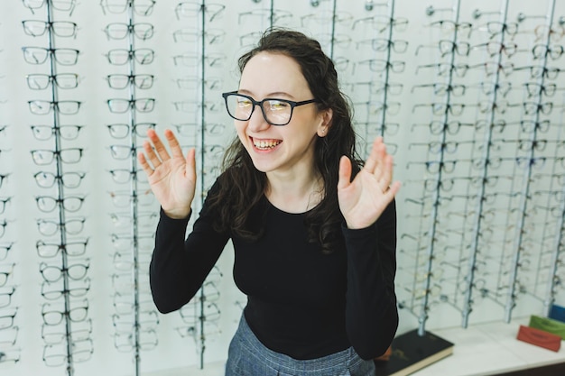 Una giovane donna sceglie gli occhiali in un negozio di ottica Stand con gli occhiali Correzione della vista Donna con gli occhiali Ritratto di una donna con gli occhiali correttivi