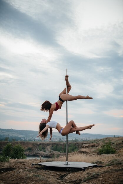 Una giovane donna sexy esegue incredibili esercizi su un palo durante un bellissimo tramonto. Danza. Sessualità.