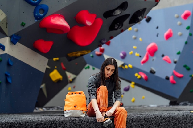 Una giovane donna si prepara a scalare una parete da arrampicata.