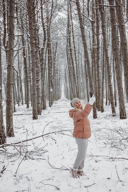 Una giovane donna si trova in una pineta e scatta foto della natura sul suo smartphone