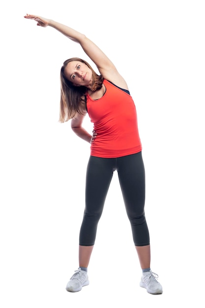 Una giovane donna snella in abbigliamento sportivo sta facendo ginnastica in piedi Attività e salute Isolato su sfondo bianco Verticale A tutta altezza