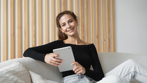 Una giovane donna sorride lavorando in un ufficio utilizzando un computer del dispositivo