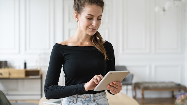 Una giovane donna sorride lavorando in un ufficio utilizzando un computer del dispositivo