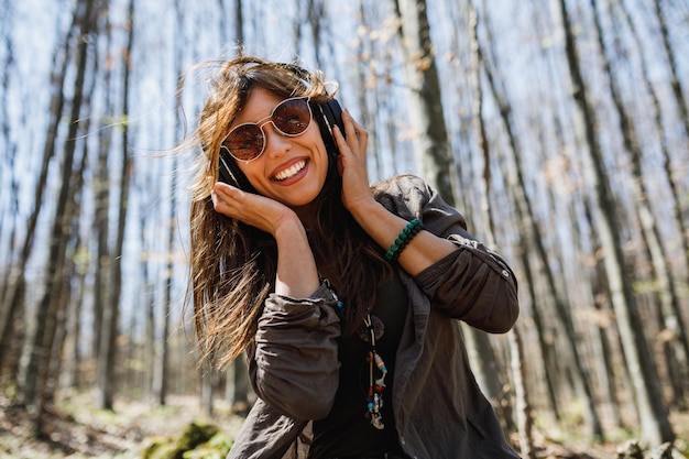 Una giovane donna sorridente che ascolta musica sulle sue cuffie mentre si gode la vita all'aria aperta.