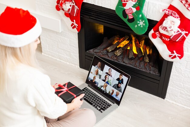 Una giovane donna sorridente che fa una videochiamata sui social network con la famiglia e gli amici il giorno di Natale.