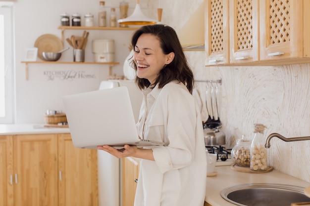 Una giovane donna sorridente in cucina si gode una conversazione video mentre fa conoscenza su un sito web una donna trascorre del tempo su un social network