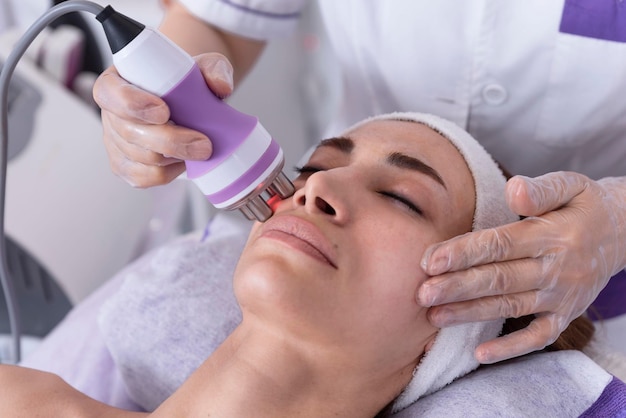 Una giovane donna sottoposta a un trattamento viso lifting con radiofrequenza Trattamento per la cura della pelle del viso ringiovanimento del viso antietà Concetto di bellezza e dermatologia