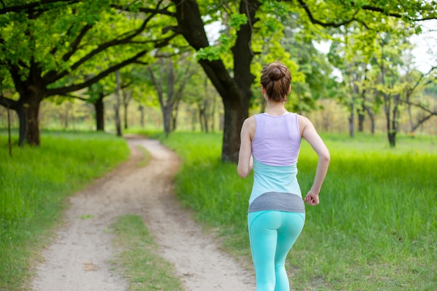 Una giovane donna sportiva in esecuzione in una foresta verde di fine estate. Sport e Benessere