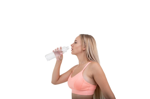 Una giovane donna sportiva in un top rosa beve l'acqua dopo un allenamento