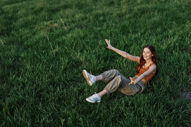 Una giovane donna sta giocando nel parco con noi nell'erba e cade a terra sorridendo felice alla luce del sole Riposandosi nella natura in armonia con il corpo