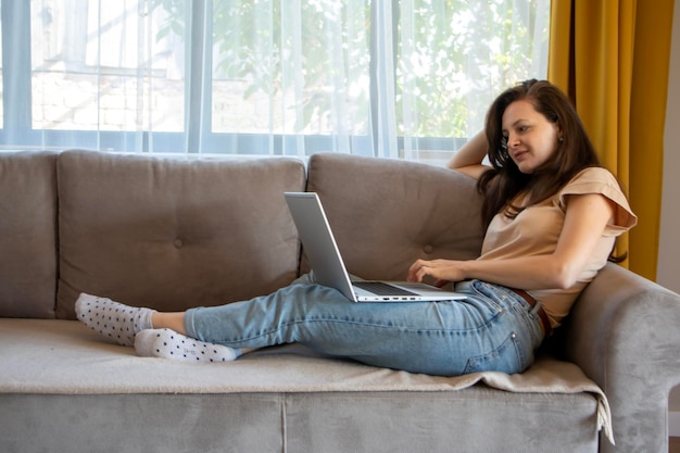 Una giovane donna sta lavorando in remoto con un laptop Comodo lavoro da casa in un appartamento accogliente ed elegante