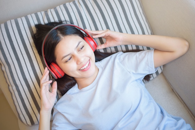 Una giovane donna sta usando l'auricolare godendo con la musica in salotto